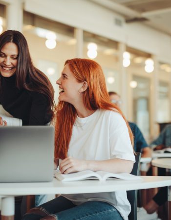 Female student talking with classmates and smiling in lecture room. University students in classroom after lecture.